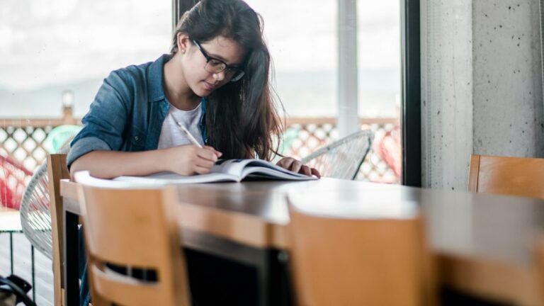 Student writing notes in a book while studying
