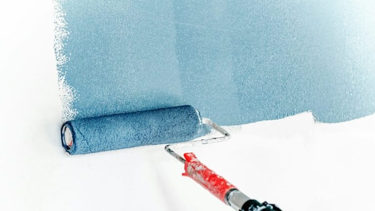 Blue paint being rolled onto a white wall with an extended roller